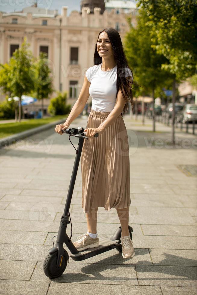 Young woman riding an electric scooter on a street photo