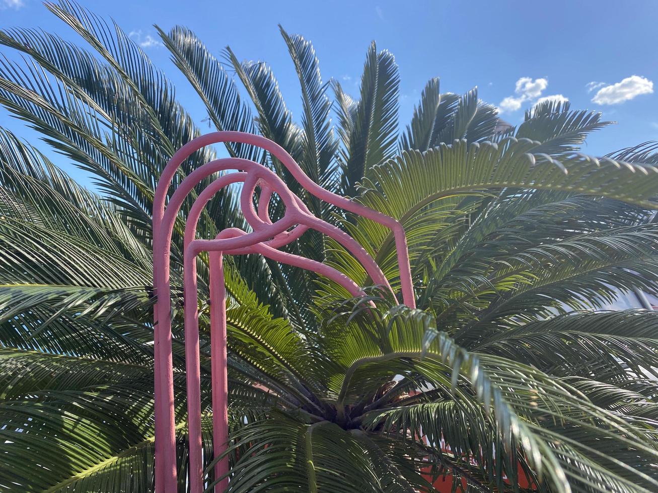 Metal flamingo figure on the background of palm leaves photo