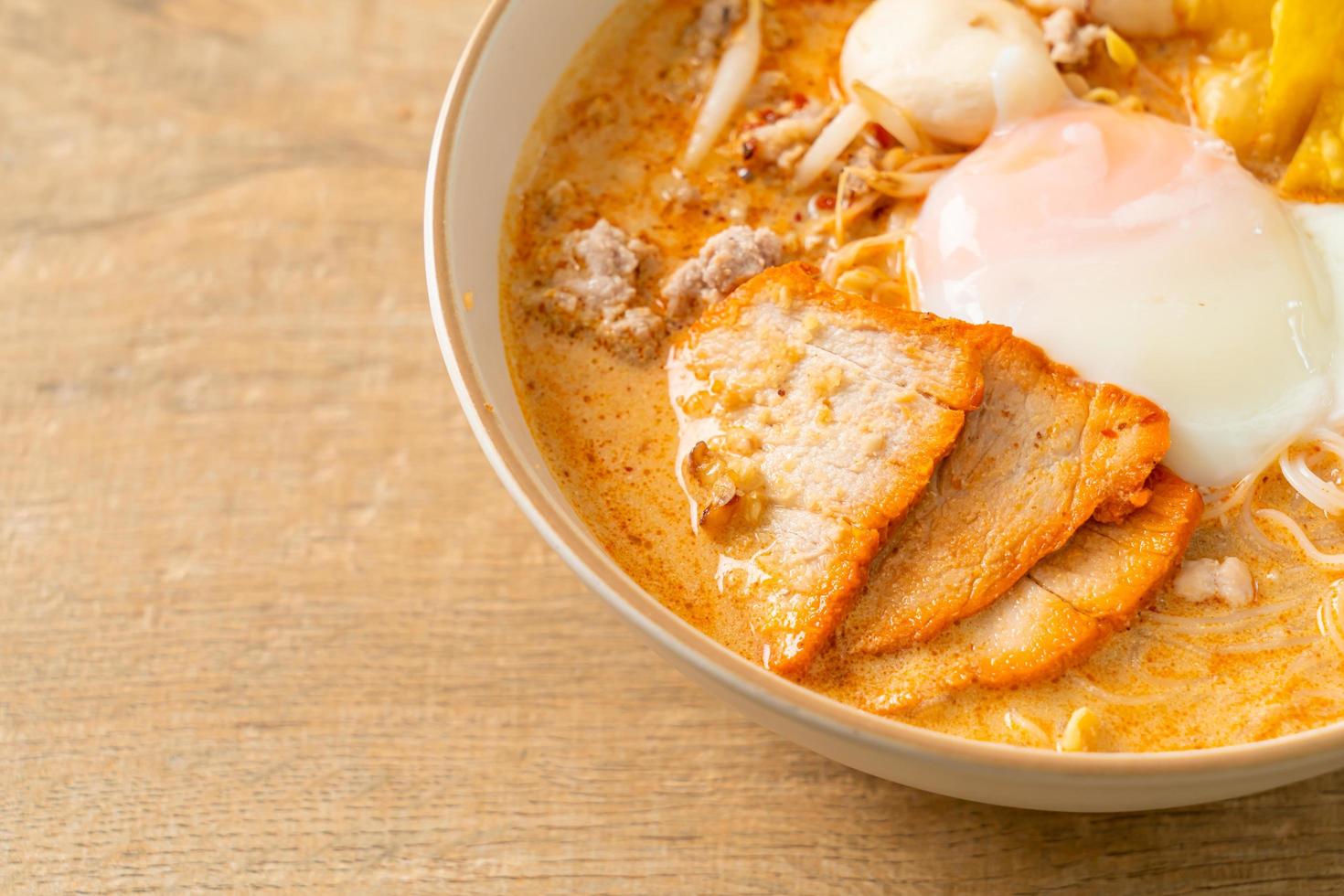 Rice vermicelli noodles with meatball, roasted pork and egg in spicy soup photo