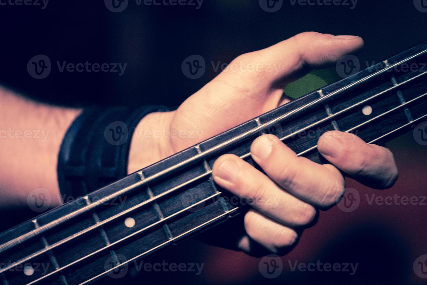 Detalle de manos tocando un bajo eléctrico foto