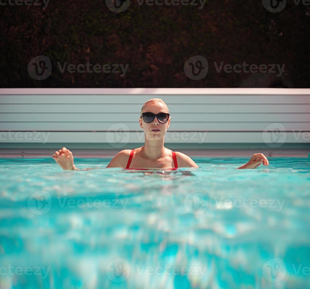 Joven hermosa chica sexy disfrutando de nadar en la piscina privada y relajarse bajo el sol foto