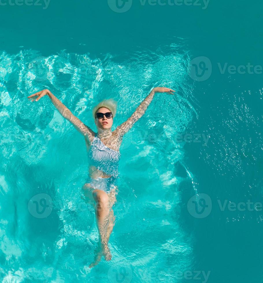 Young beautiful sexy girl enjoying swimming in the private pool and relaxing in the sun photo