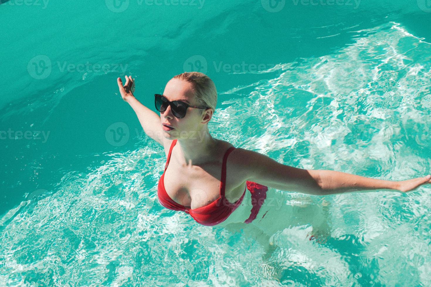 Young beautiful sexy girl enjoying swimming in the private pool and relaxing in the sun photo