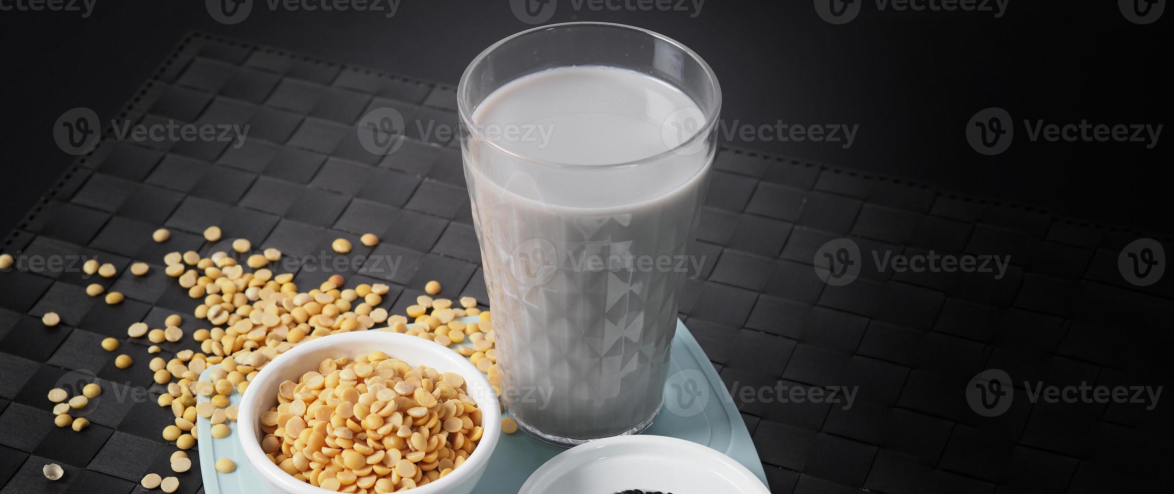 Soy milk blended with black sesame in clear glass on black plate mat. photo