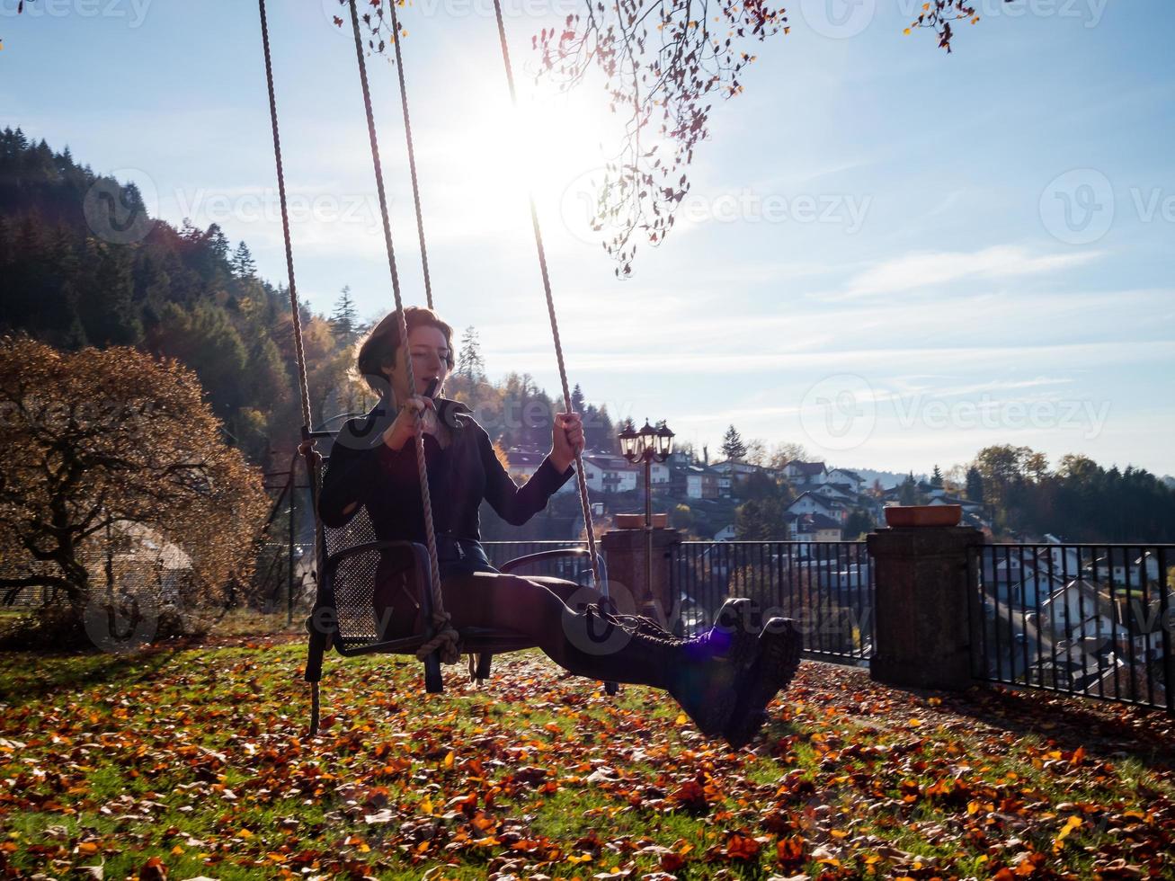 A young girl is swinging on a swing. Sunny day. photo