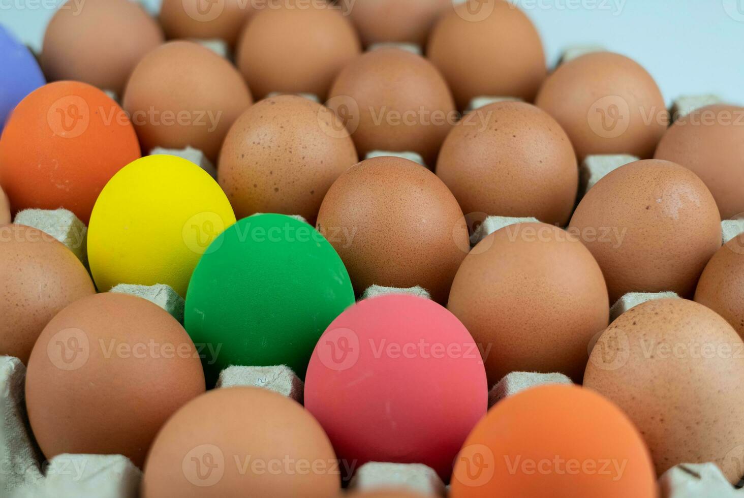 Eggs carton with chicken colorful easter egg lined up in rows at white background photo