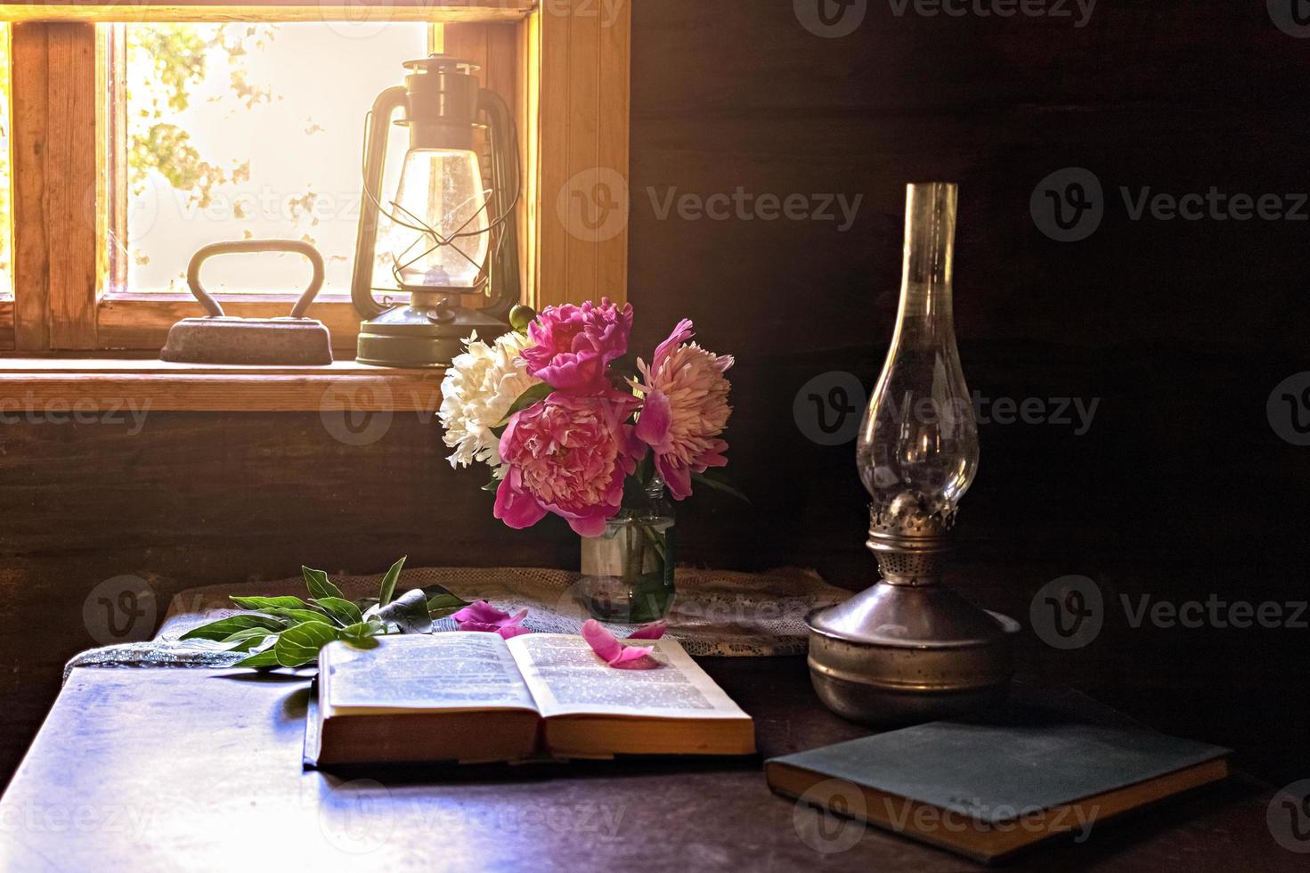 Still life of vintage items and a bouquet of peonies on a table by the window in an old village house. photo