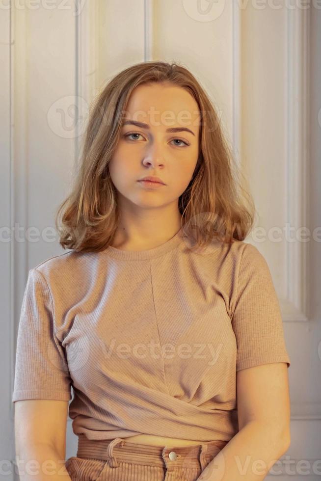 A cute stylish young girl is sitting in the doorway of her room. Teenager. Sadness photo