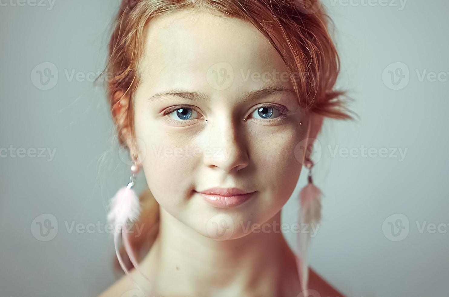 Close-up portrait of a young girl with festive makeup for a party. Valentine's Day. Earrings-feathers in the ears of the model photo