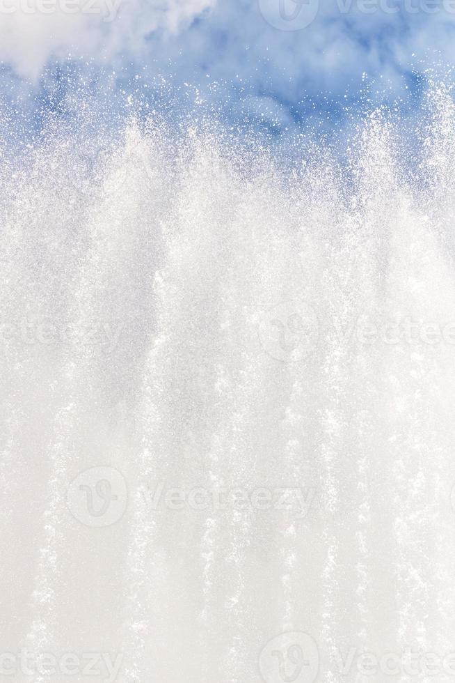 Fondo de chorros de agua y salpicaduras de fuente contra un cielo azul con nubes foto