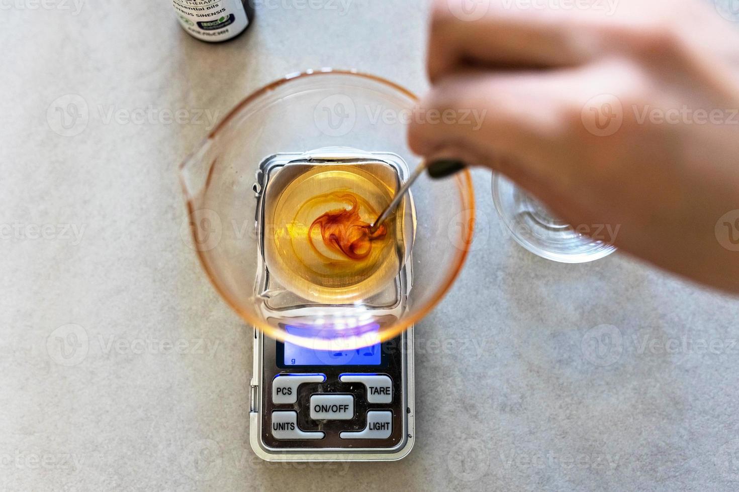 A soap-maker woman weighs aromatic oils for making cosmetics on a kitchen scale. Home spa. Small business photo