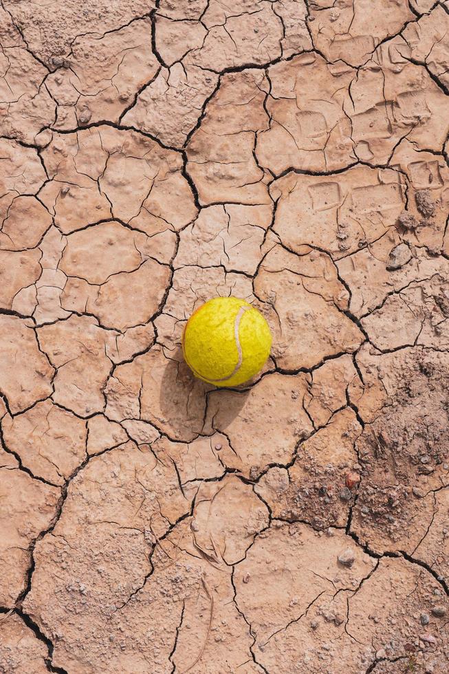 yellow tennis ball on the desert ground, global warming photo