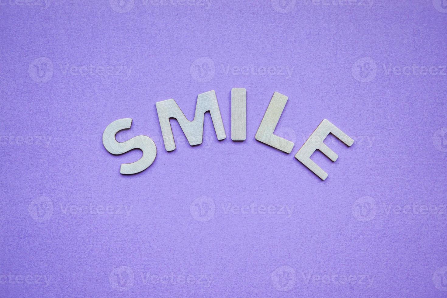 Sonrisa palabra con letras de madera sobre fondo morado foto