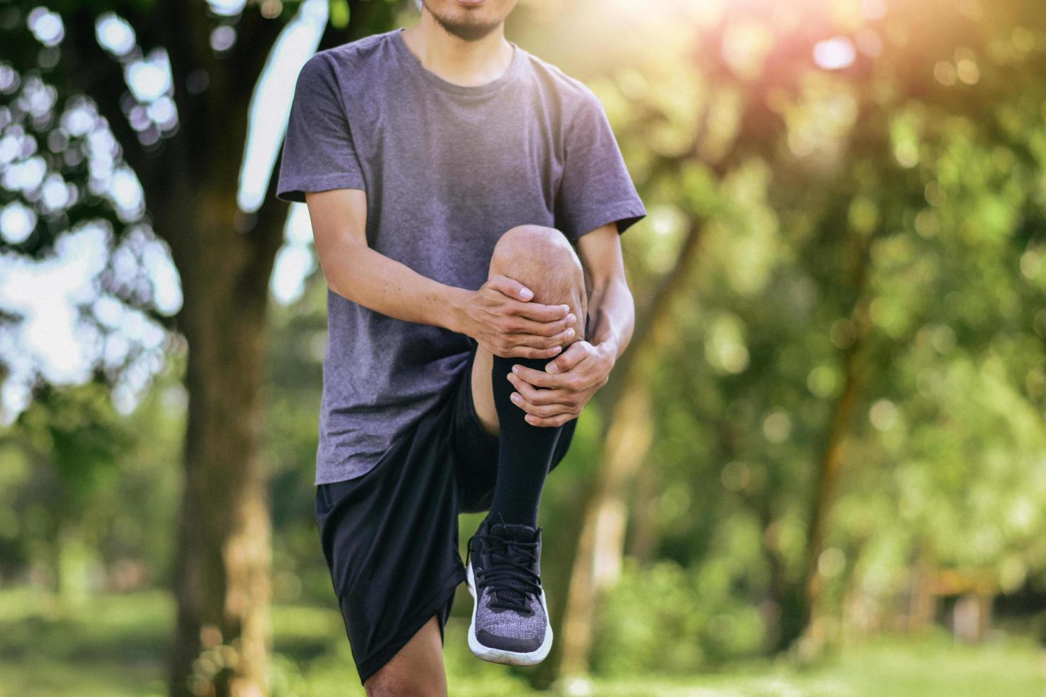 Hombre estirando los músculos de las piernas antes de hacer ejercicio, entrenamiento de atleta joven corredor masculino foto