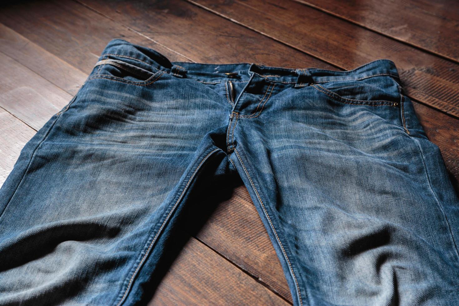 Blue mens jeans denim pants on wooden background. Fashion clothing concept. photo