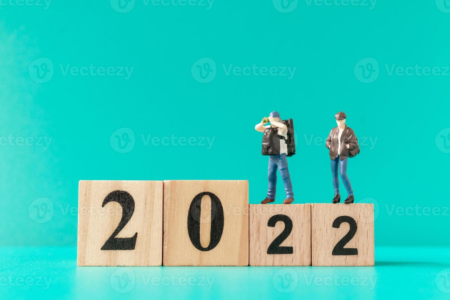 Miniature backpacker and tourist standing on wooden block number 2022 photo