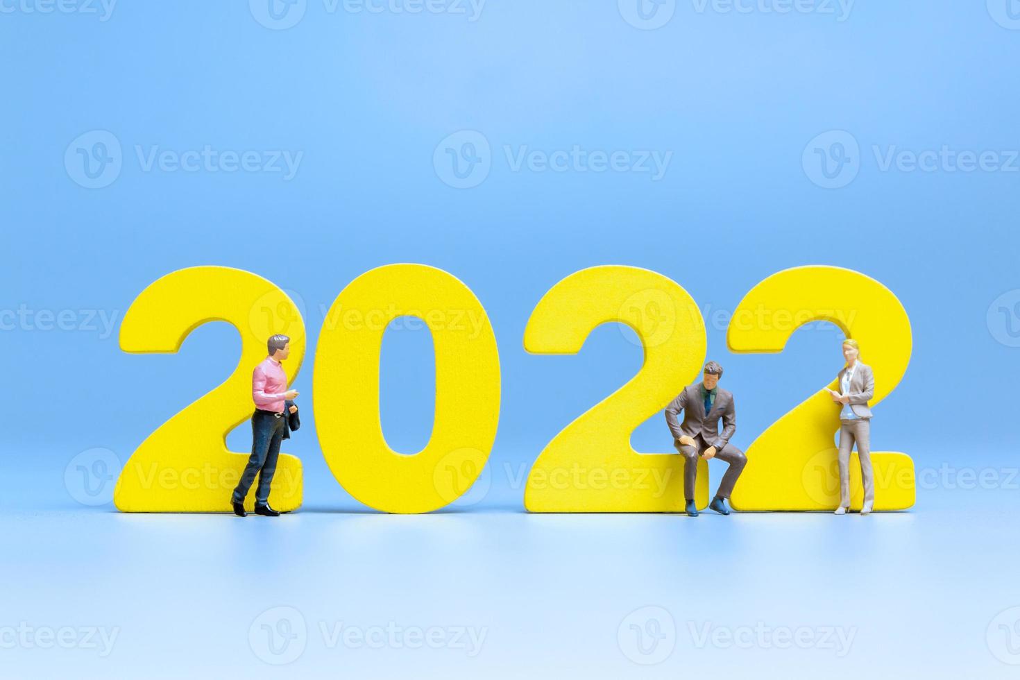 Gente de negocios en miniatura de pie en el número 2022 foto