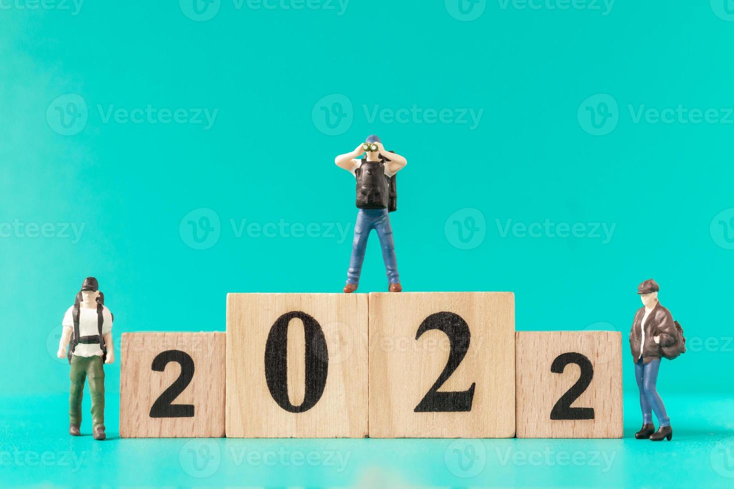 Miniature backpacker and tourist standing on wooden block number 2022 photo