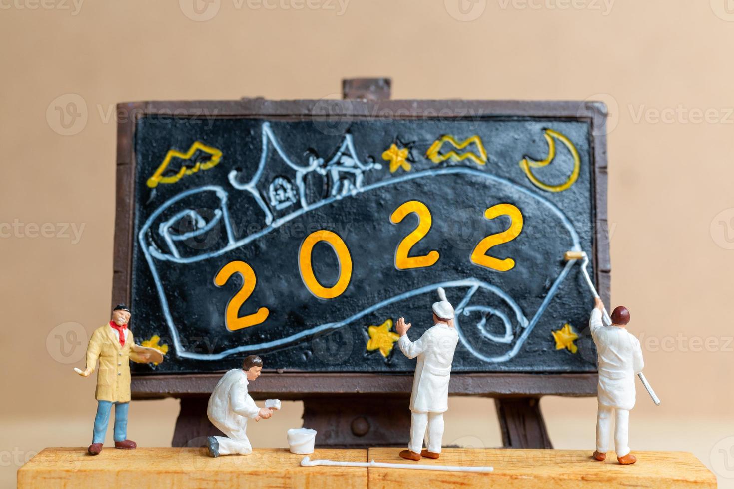 Miniature people worker team painting number 2022 on black board photo