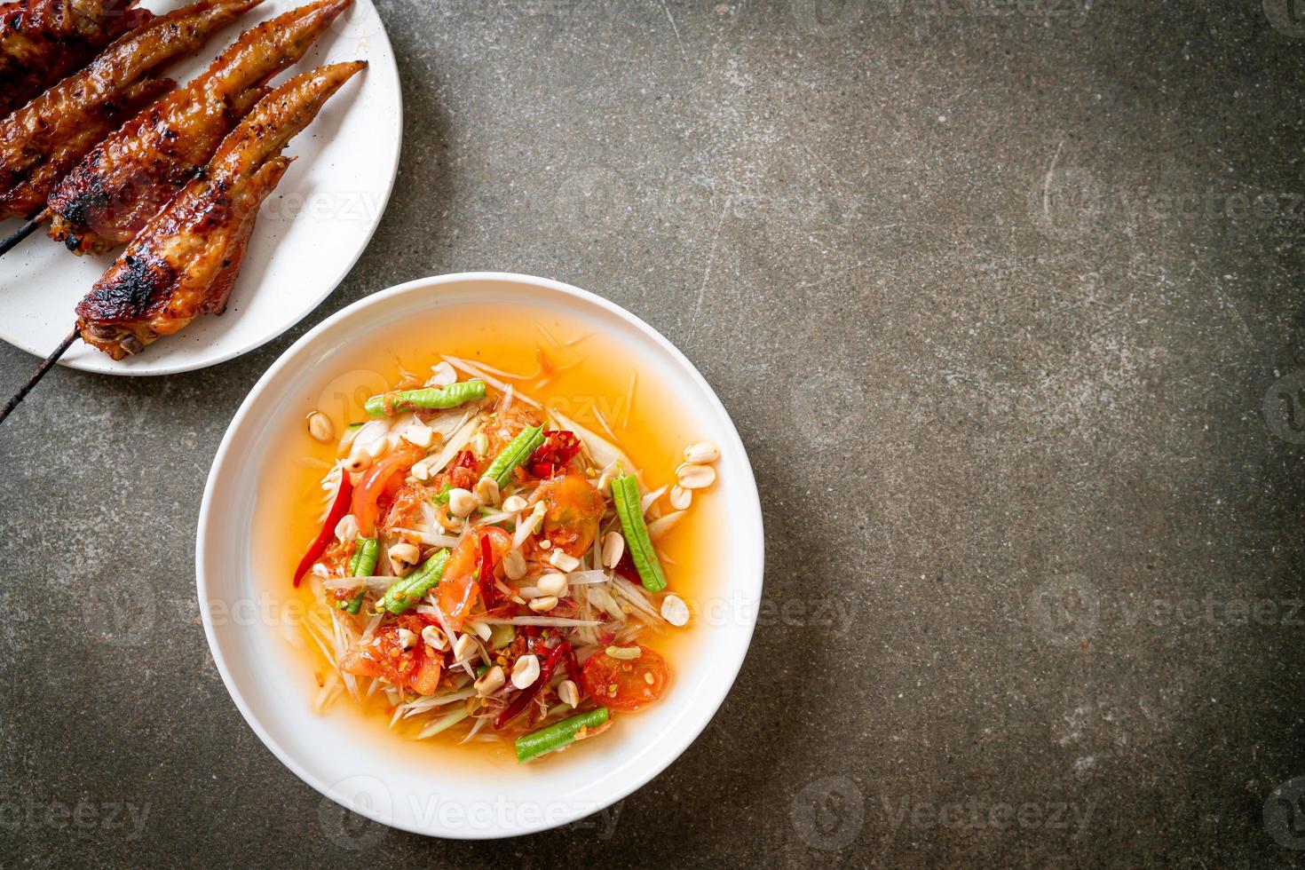 Papaya spicy salad with grilled chicken - Thai traditional street food style photo