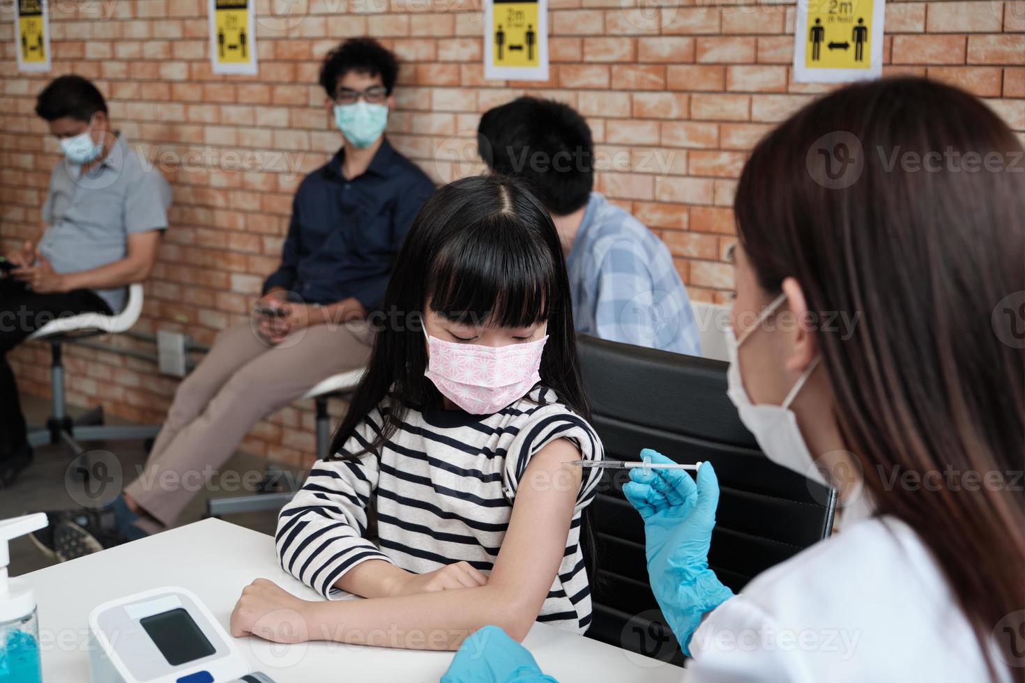 médico inyecta a una paciente chica con gente haciendo cola. foto