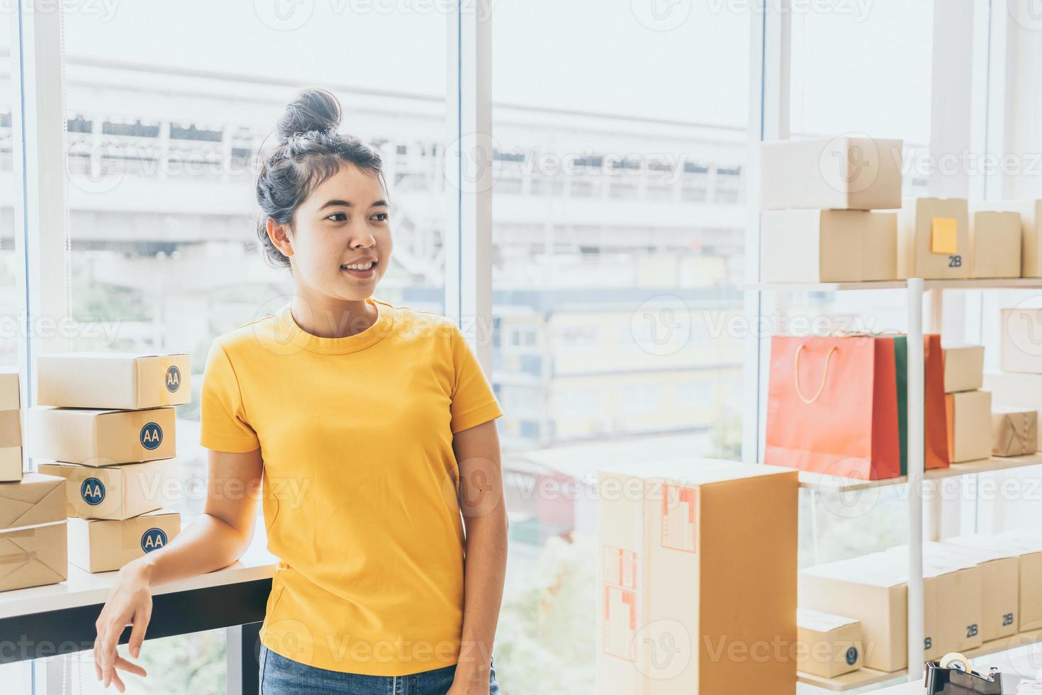 Asian woman business owner working at home with packing box on the workplace - online shopping SME entrepreneur or freelance working concept photo