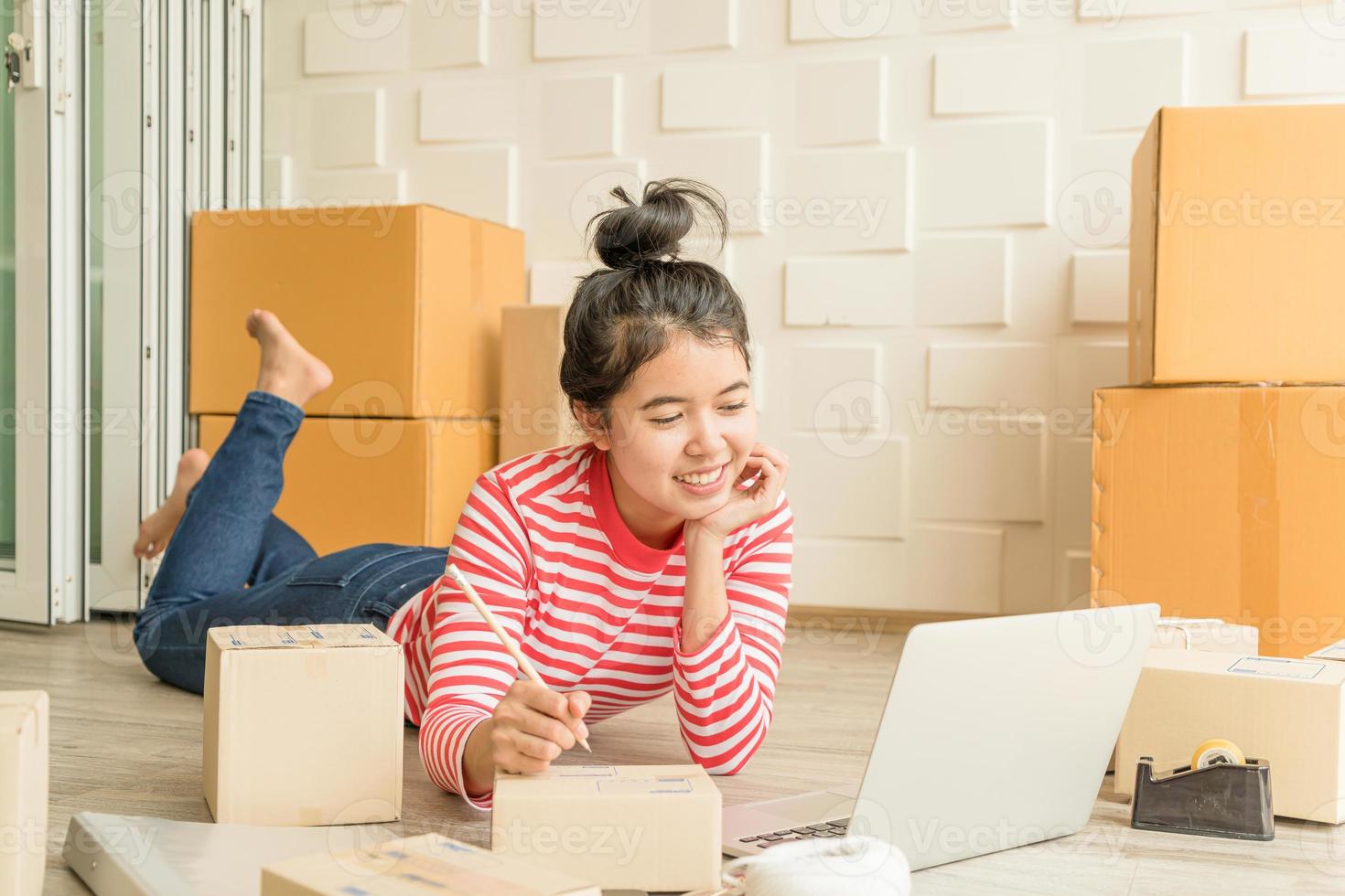 Mujer asiática propietaria de una empresa que trabaja en casa con una caja de embalaje en el lugar de trabajo - emprendedor pyme de compras en línea o concepto de trabajo independiente foto