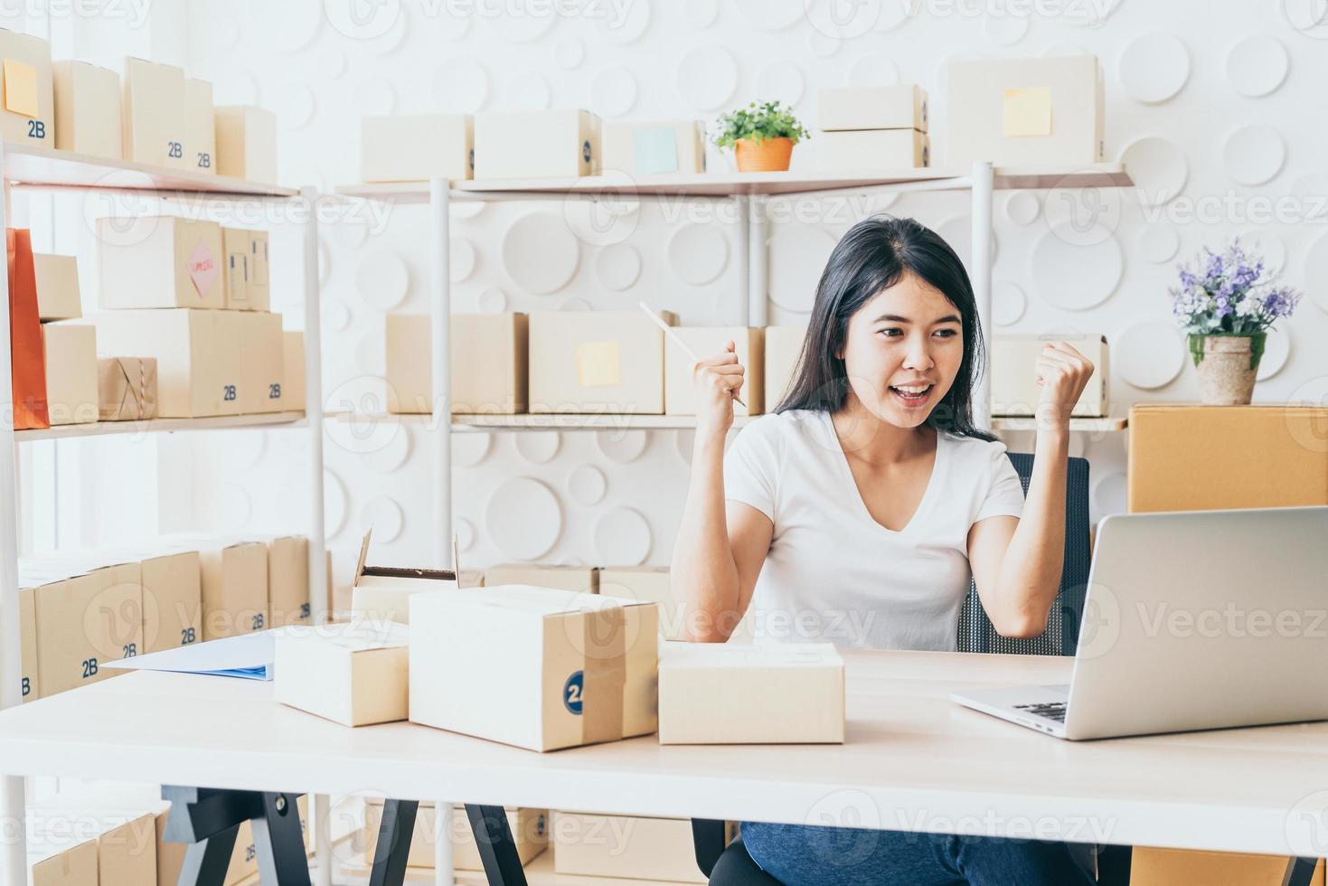 Mujer joven feliz después de un nuevo pedido del cliente, propietario de un negocio en casa - emprendedor pyme de compras en línea o concepto de trabajo independiente foto