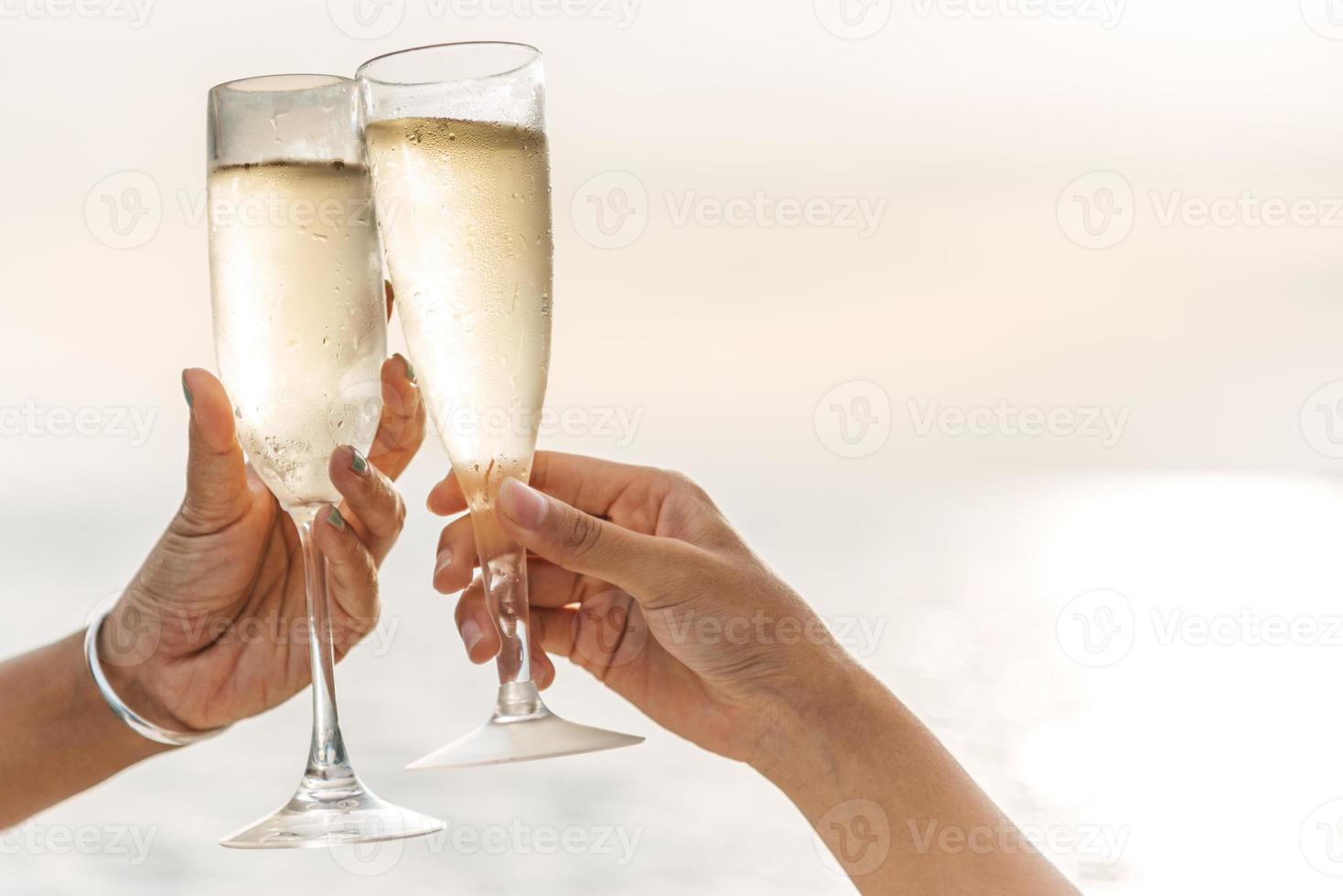 Hand holding a glass drinking wine on Sunset sea background. photo