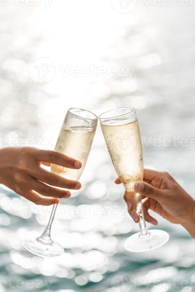 mano sosteniendo un vaso bebiendo vino en el fondo del mar al atardecer. foto