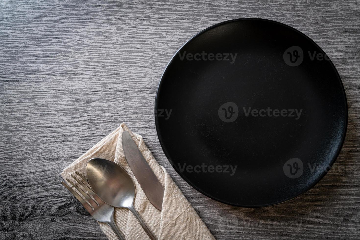 Empty plate or dish with knife, fork, and spoon on wood tile background photo