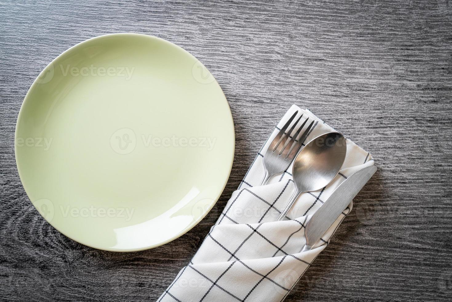 Empty plate or dish with knife, fork, and spoon on wood tile background photo