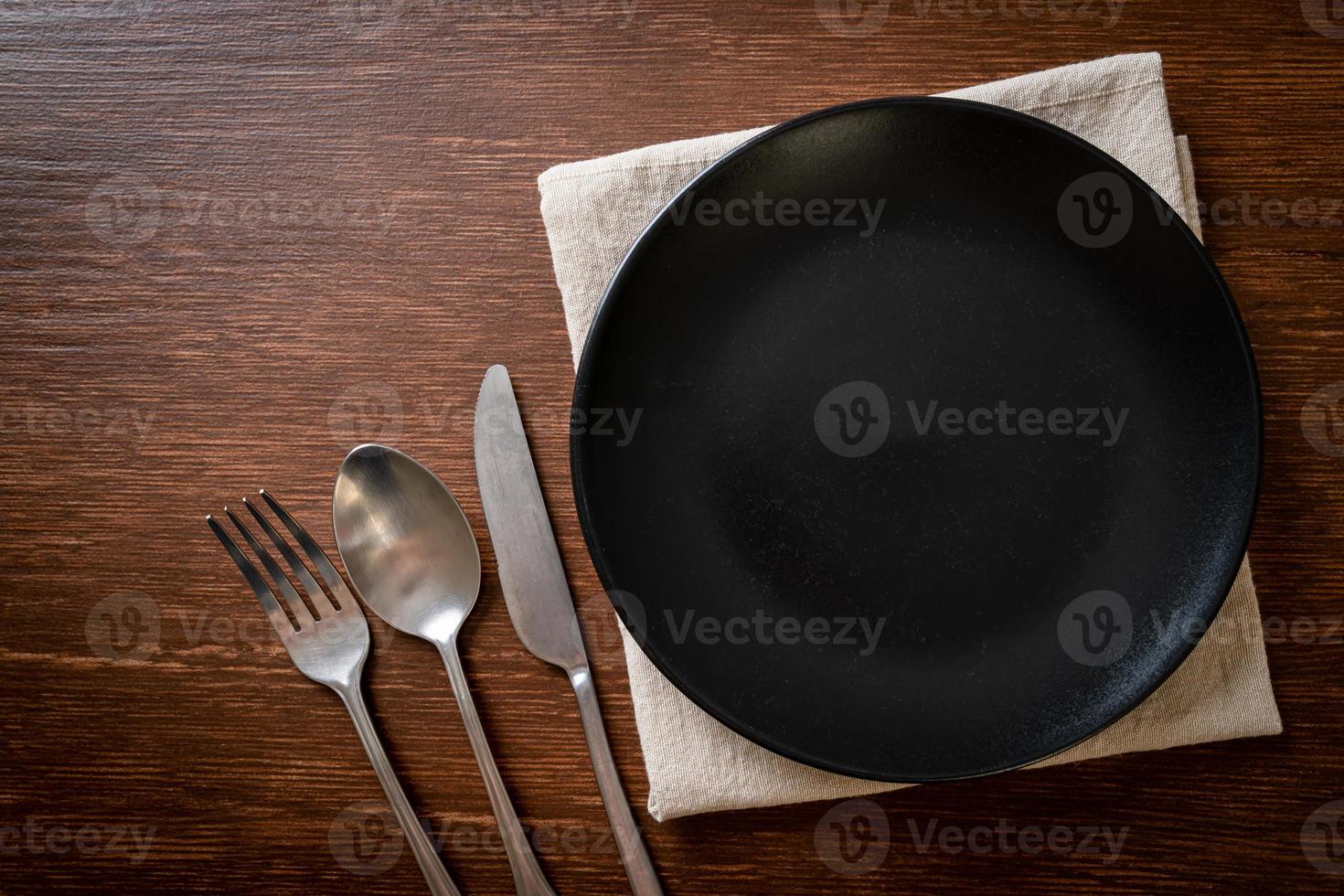 Empty plate or dish with knife, fork, and spoon on wood tile background photo