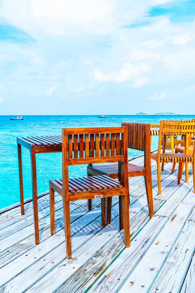 Mesa y silla de madera al aire libre vacía con fondo de vista al mar en Maldivas foto