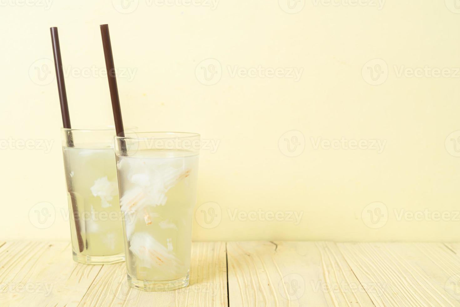 Coconut water or coconut juice in glass with ice cubes photo