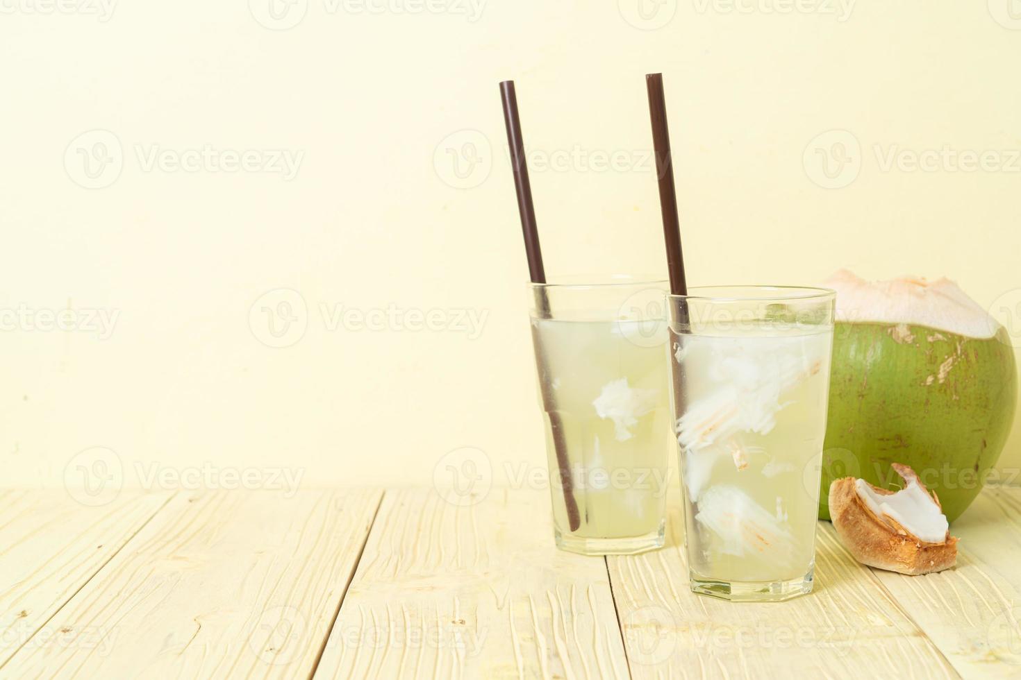 Coconut water or coconut juice in glass with ice cubes photo