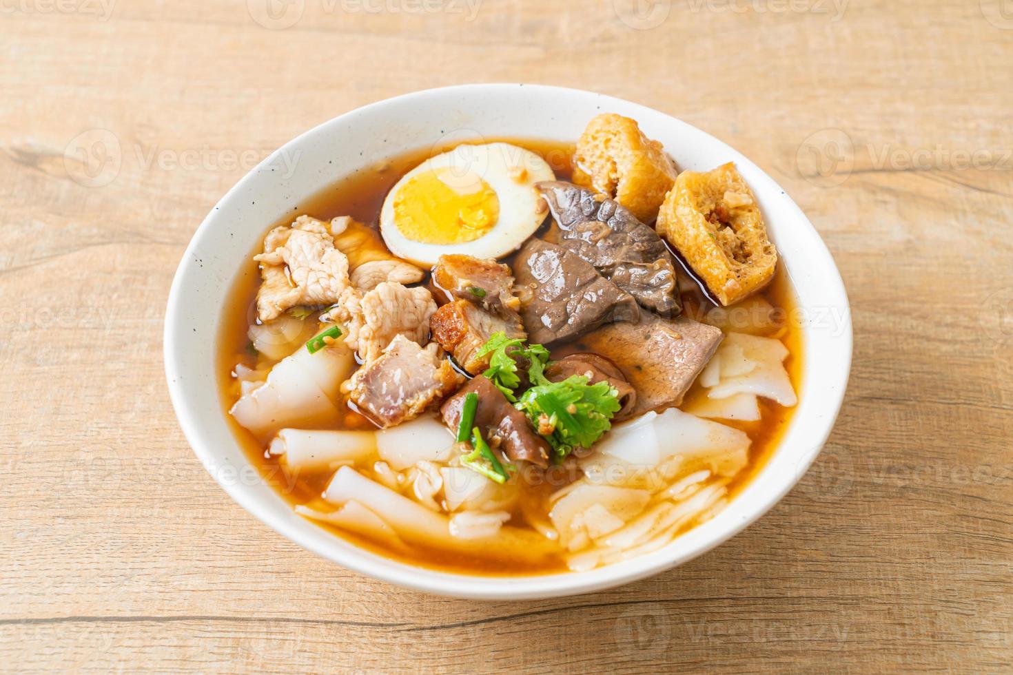 Paste of rice flour or boiled Chinese pasta square with pork in brown soup - Asian food style photo