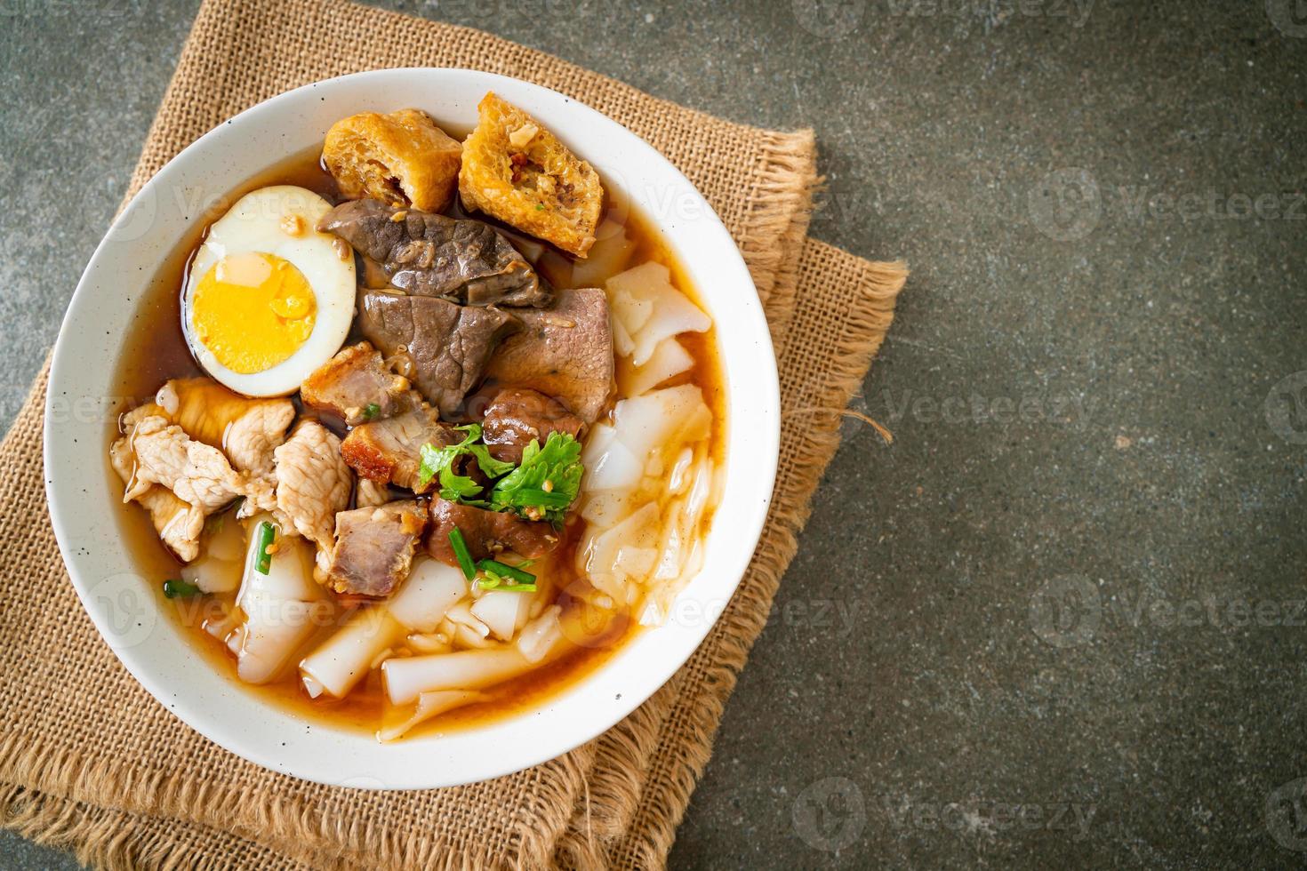 Paste of rice flour or boiled Chinese pasta square with pork in brown soup - Asian food style photo
