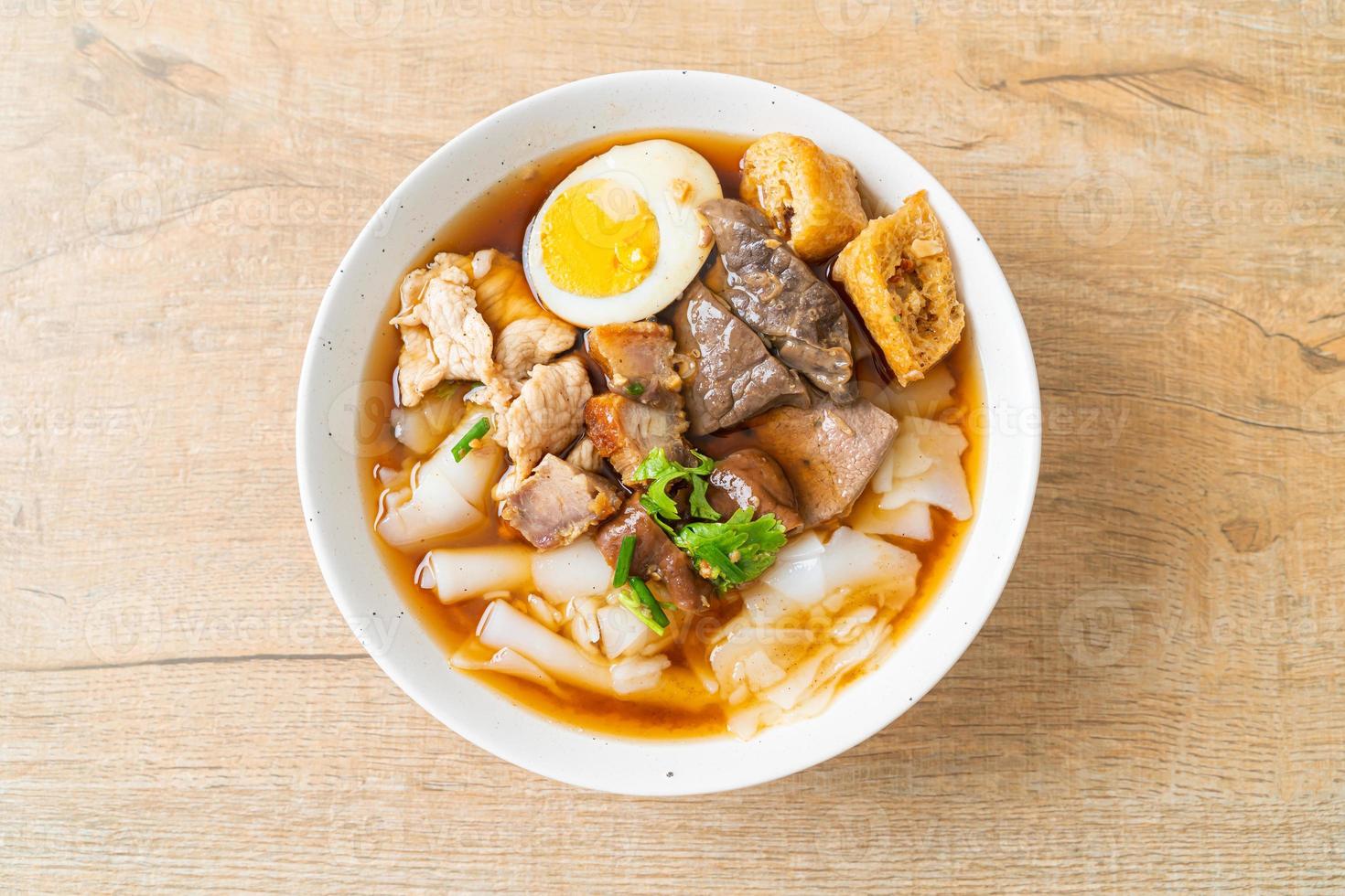 Paste of rice flour or boiled Chinese pasta square with pork in brown soup - Asian food style photo