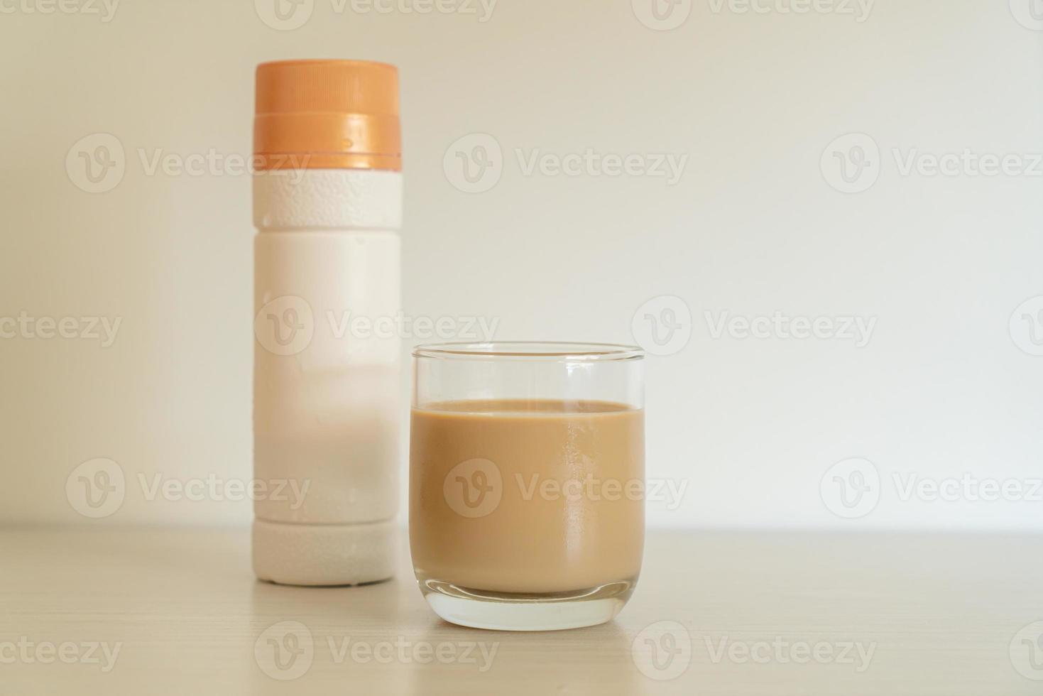 Vaso de café con leche con botellas de café listas para beber en la mesa foto