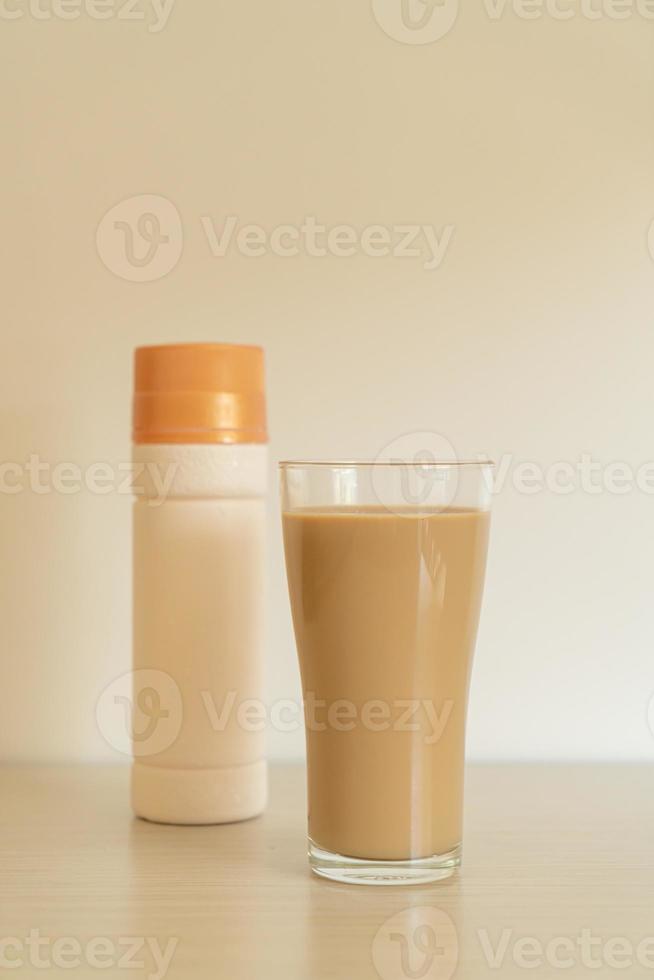 Vaso de café con leche con botellas de café listas para beber en la mesa foto