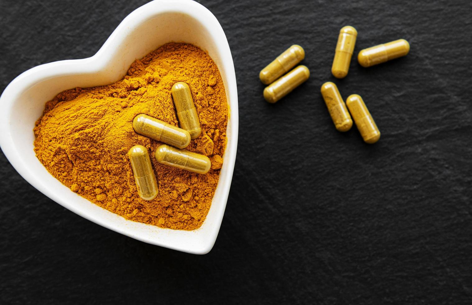 Turmeric powder and turmeric pills on a black concrete background photo