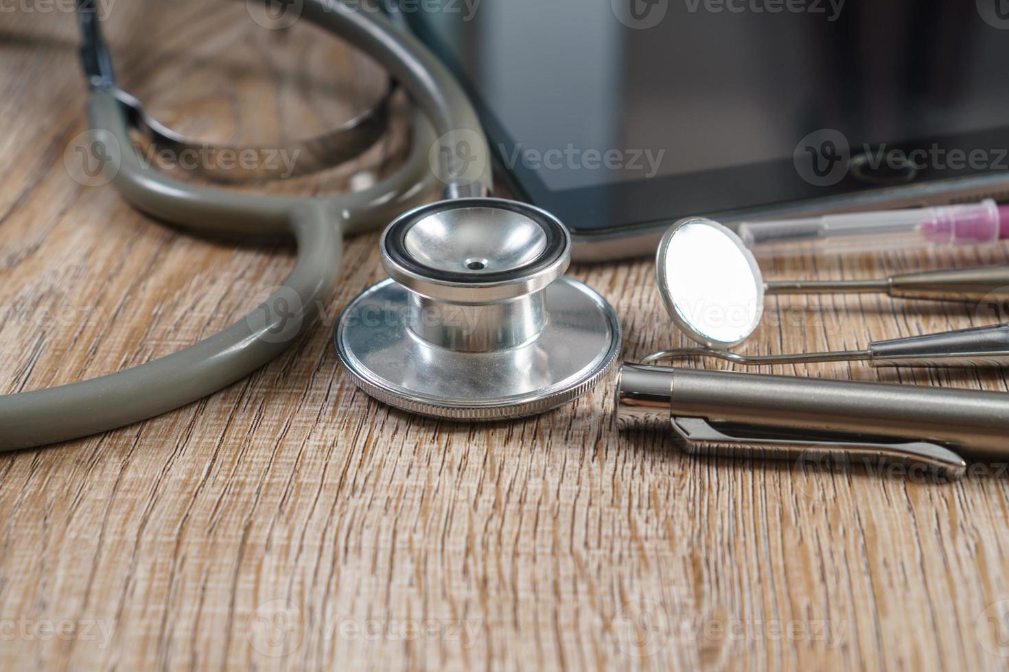 Stethoscope with syringe and dental tools on wooden table background photo