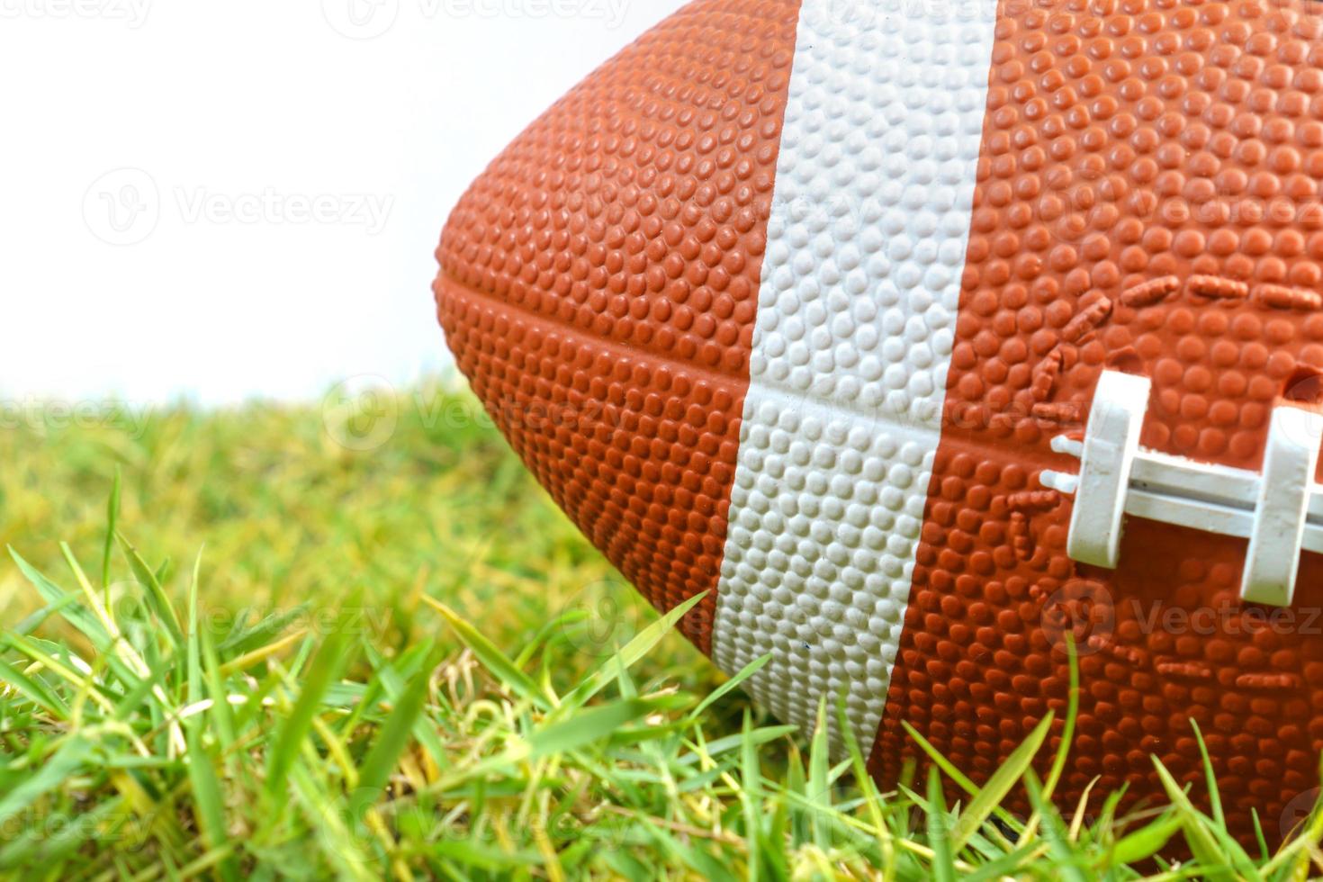 American Football ball on green grass isolated on white background photo