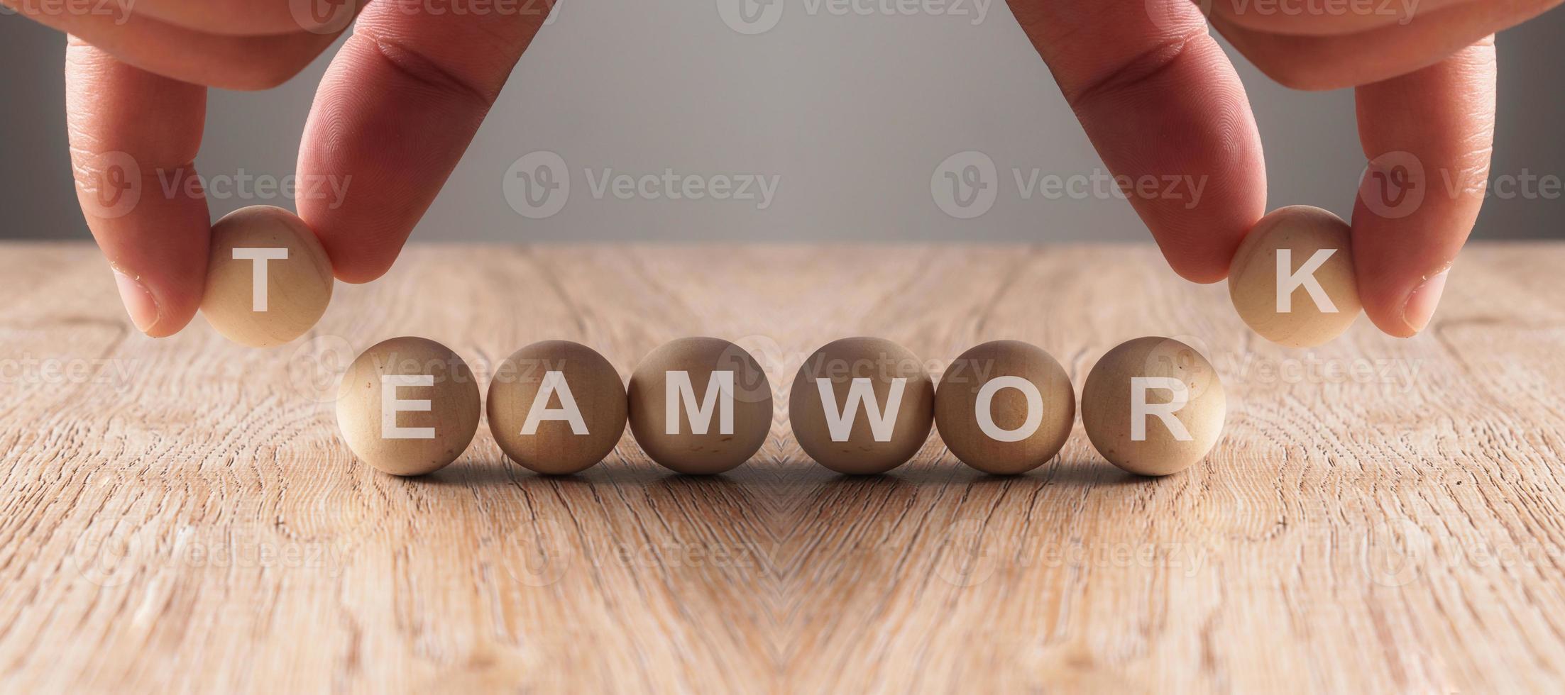 Hands putting on teamwork word written in wooden ball photo