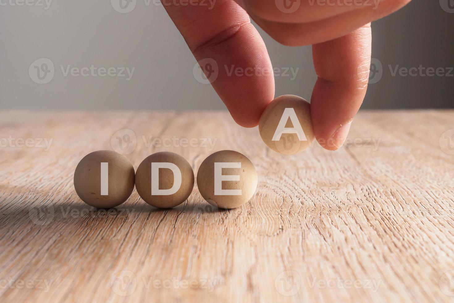 Poner la mano en la palabra idea escrita en bola de madera foto