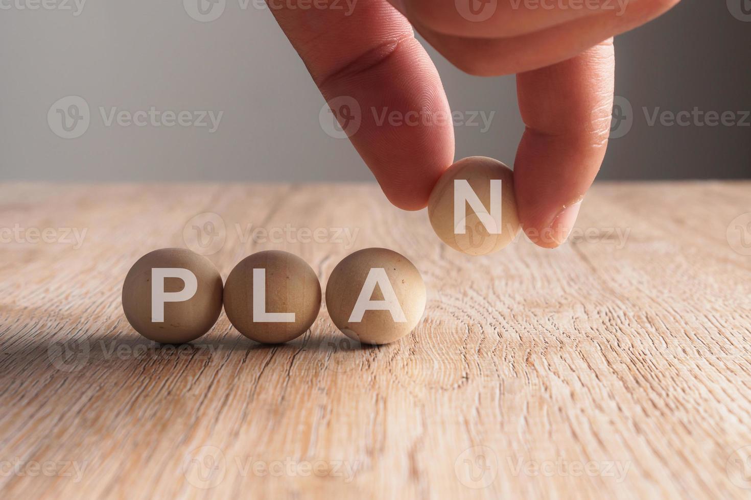 Mano poniendo en plan palabra escrita en bola de madera foto