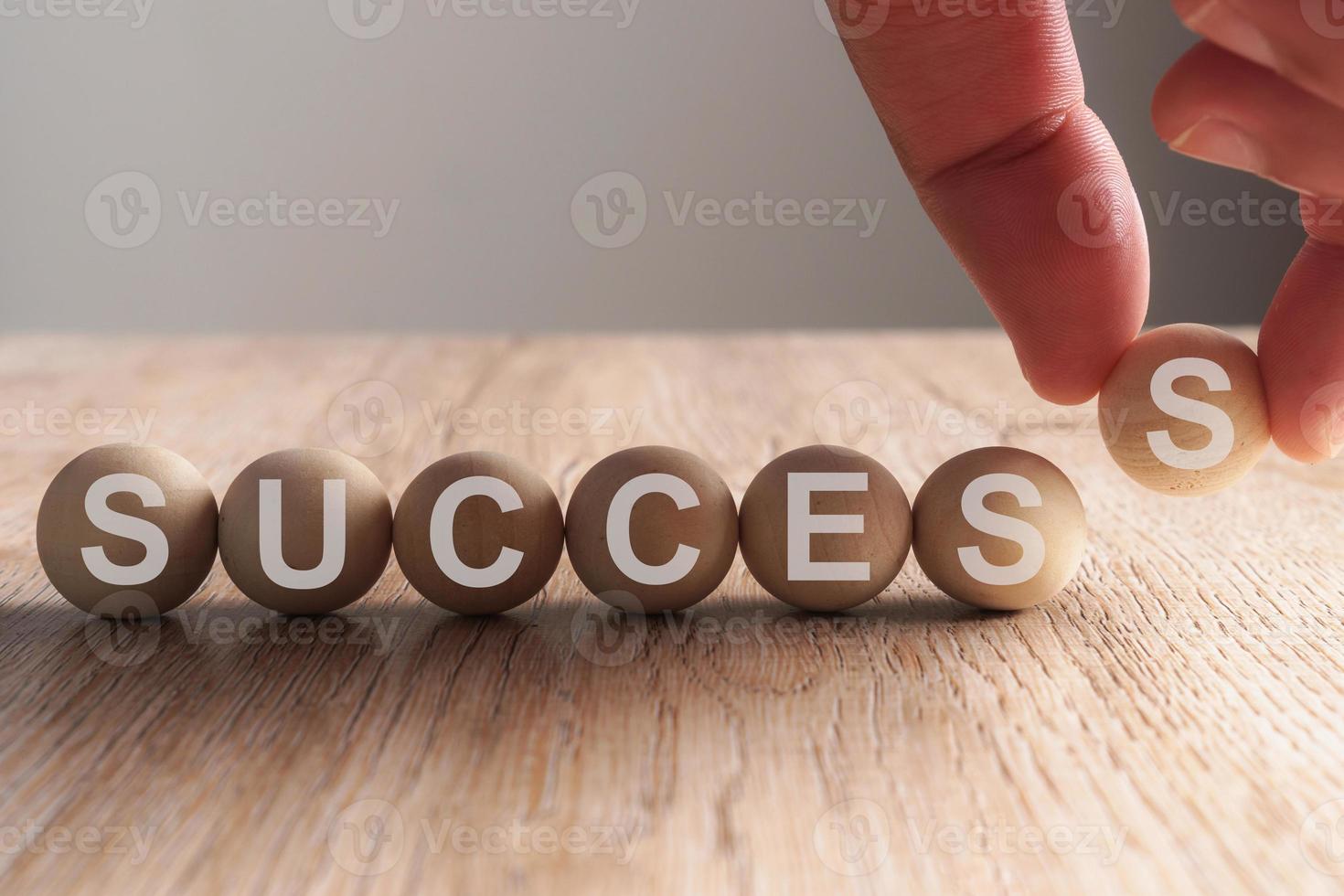 Hand putting on success word written in wooden ball photo