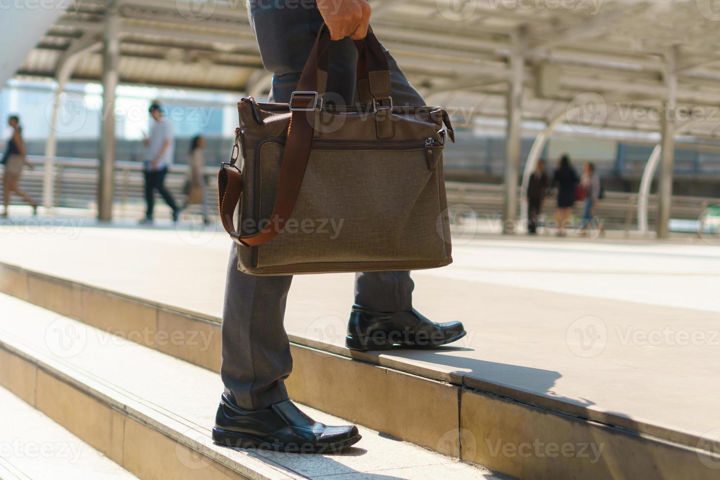 Businessman walking in the city and holding briefcase photo