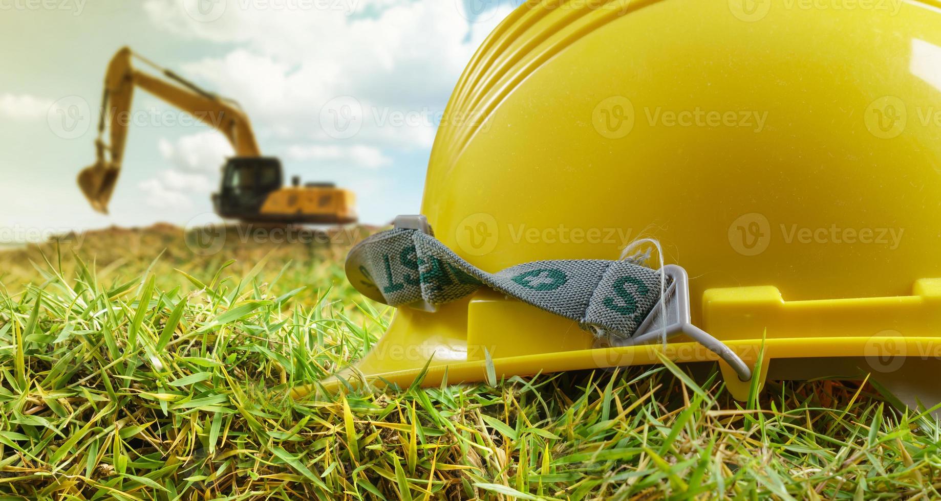 Yellow helmet and excavator working at construction site photo